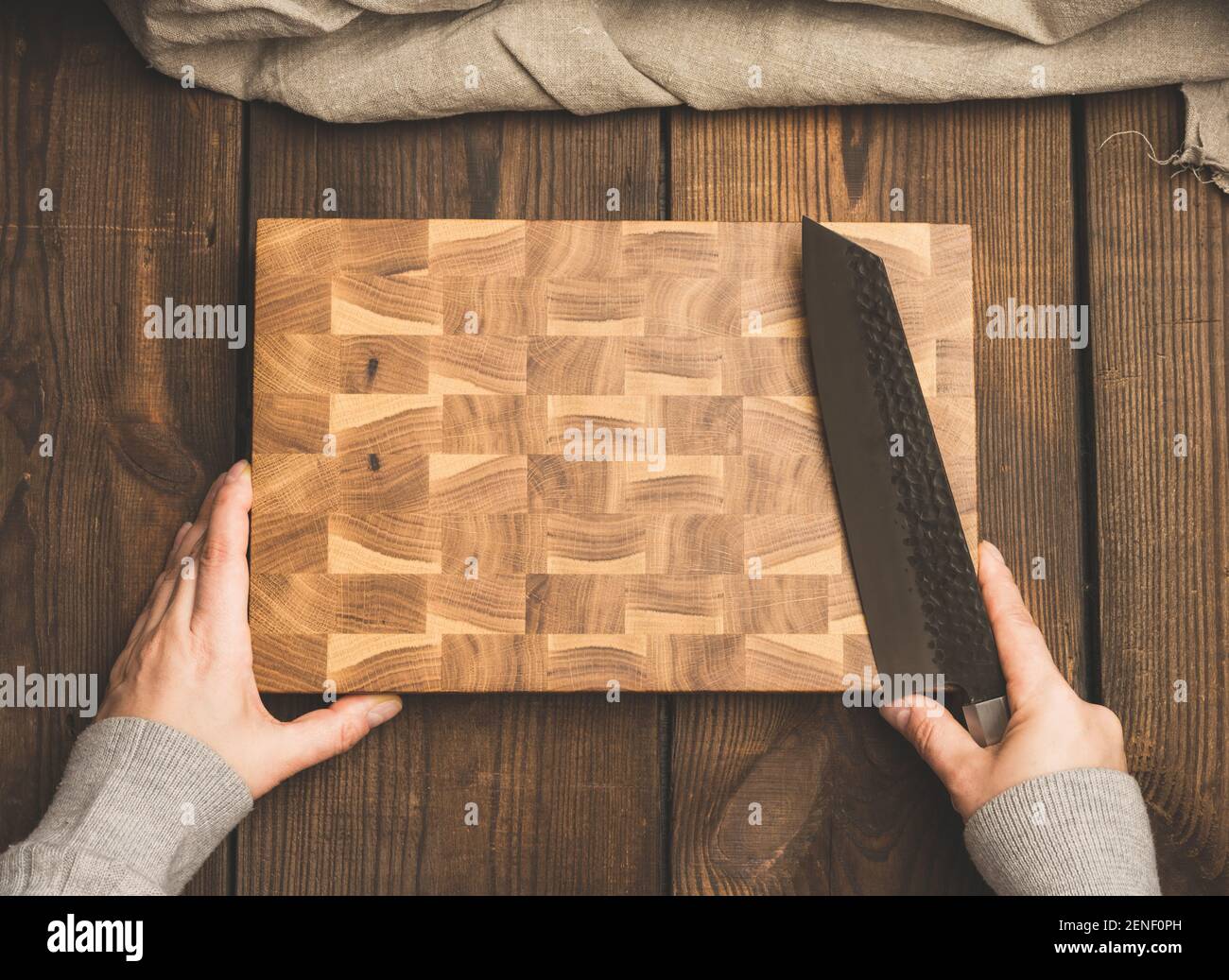 empty rectangular wooden board and female hands with a knife, top view Stock Photo