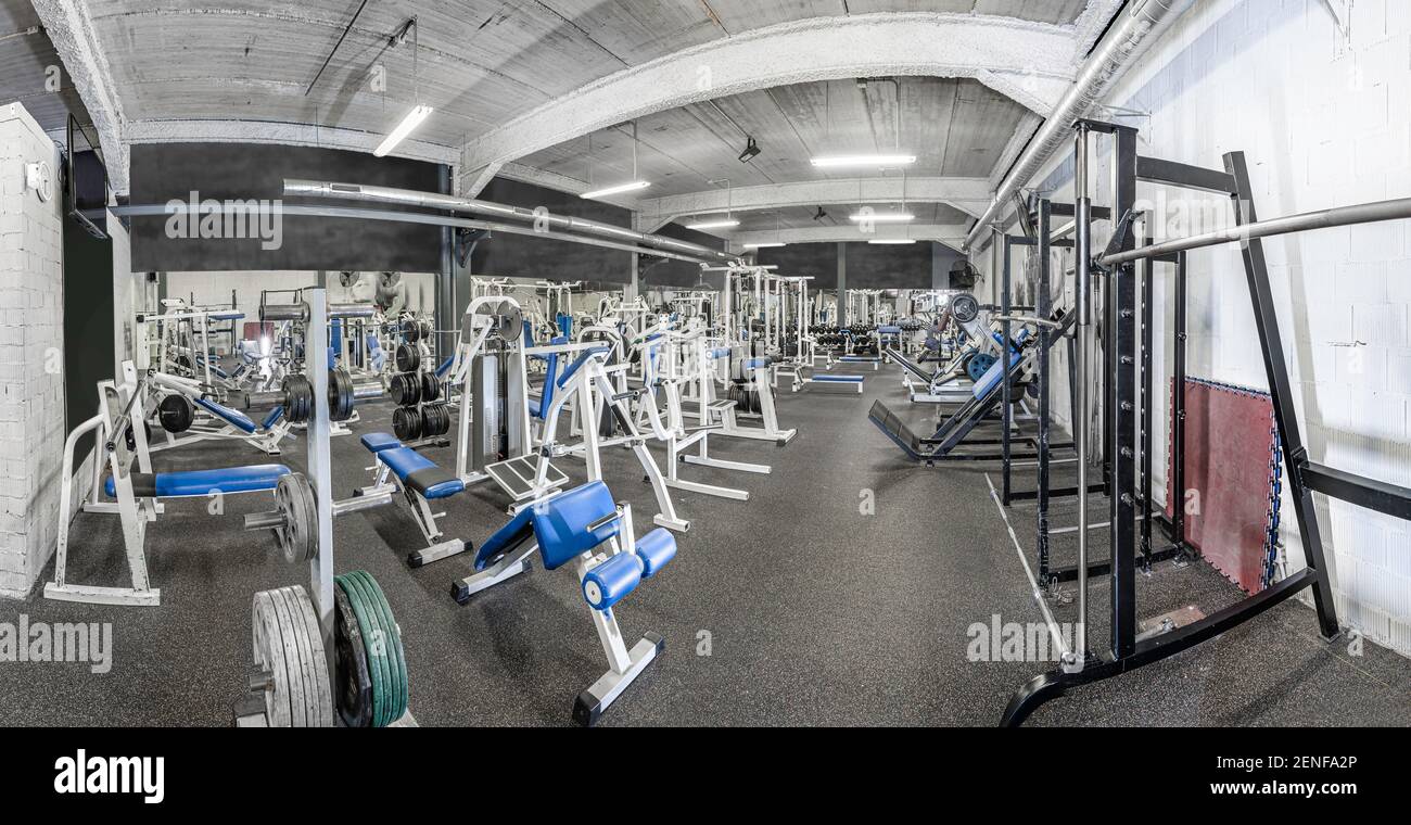 Panorama of a classic bright gym. White sport equipment and blue seats ...