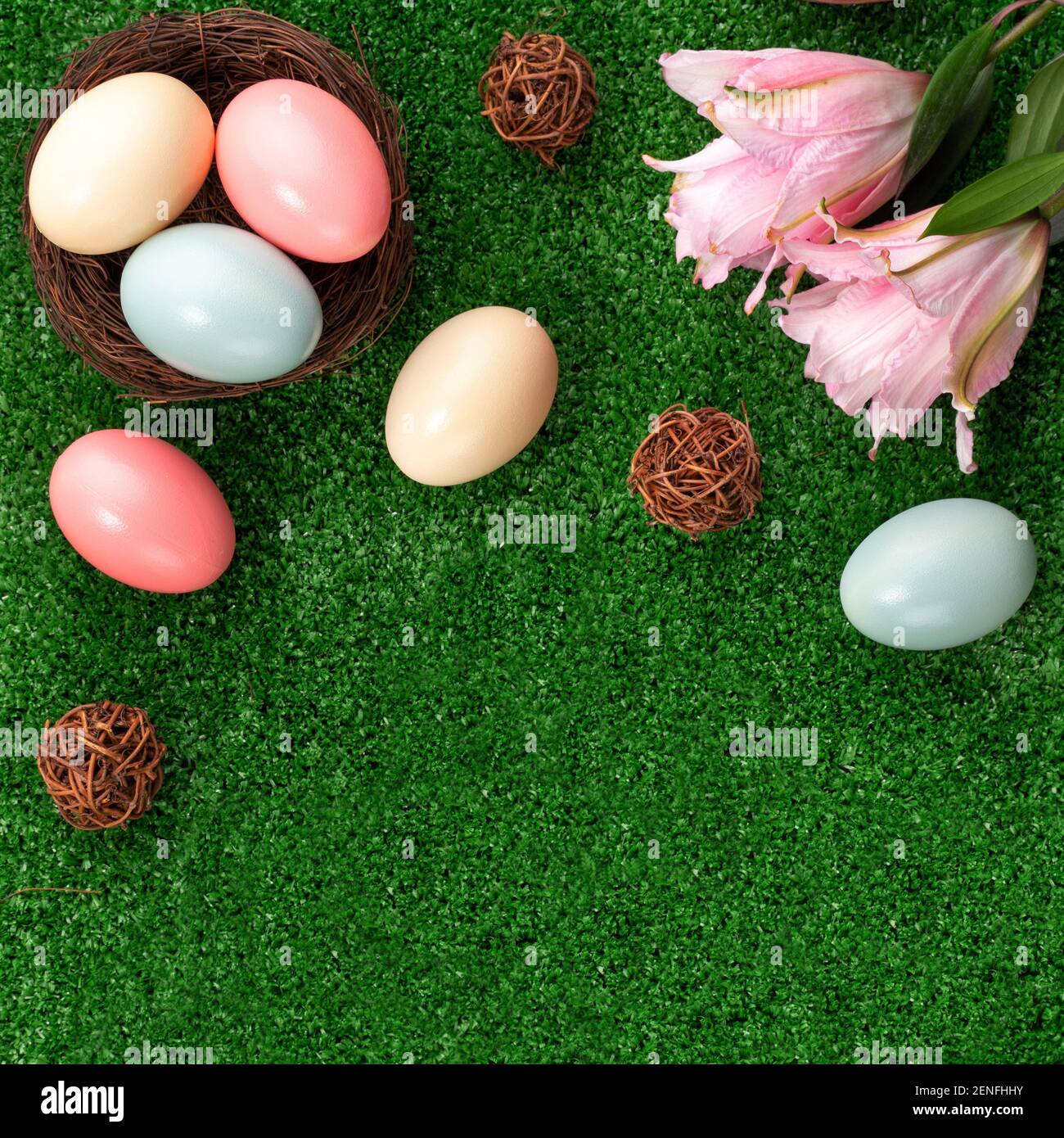 Colorful Easter eggs in the nest with pink lily flower on a lawn grass ...
