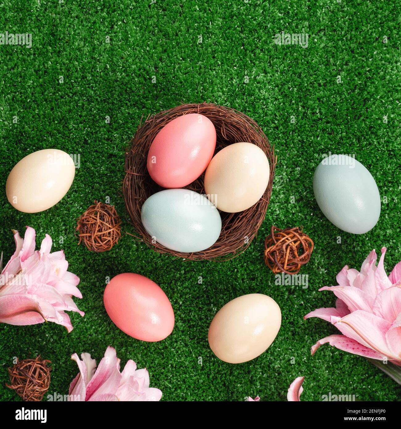 Colorful Easter eggs in the nest with pink lily flower on a lawn grass ...