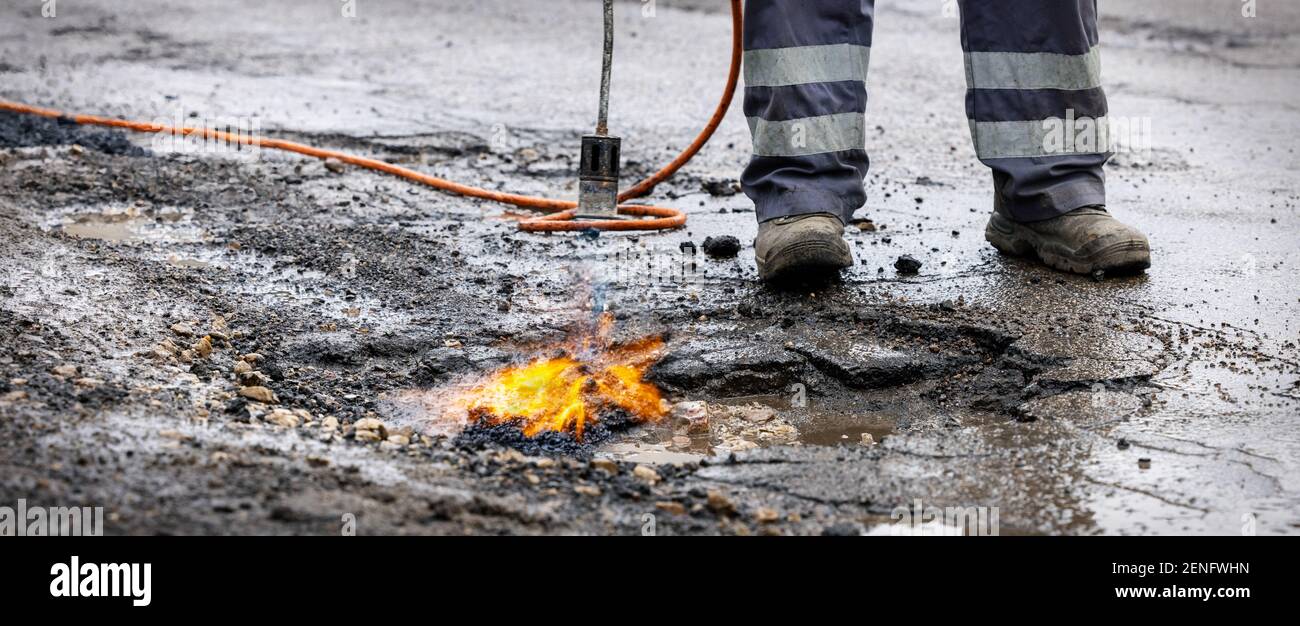 road worker prepare pothole with gas torch flame for repairing. copy space Stock Photo