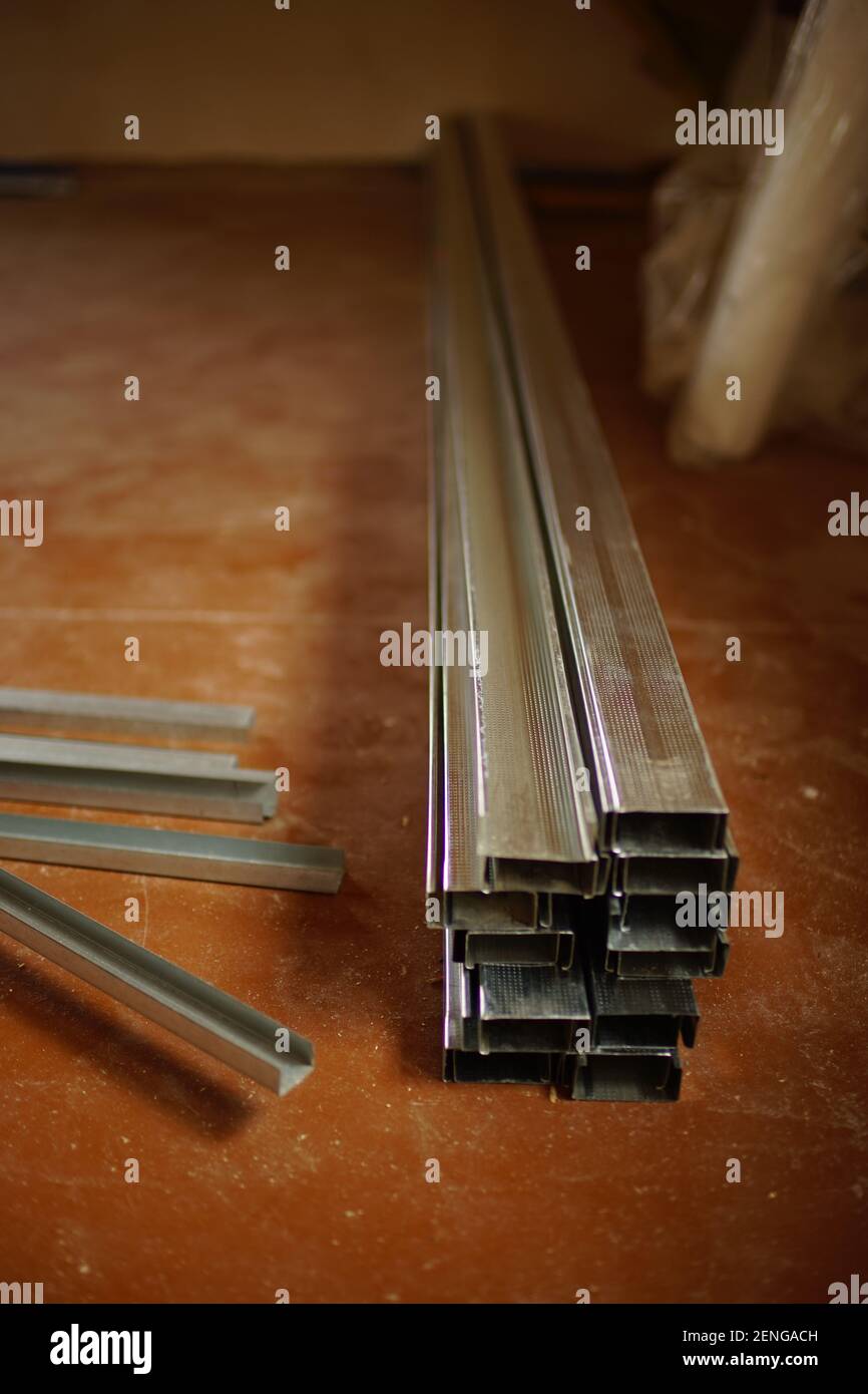 new drywall profiles lie on the dirty wooden floor Stock Photo