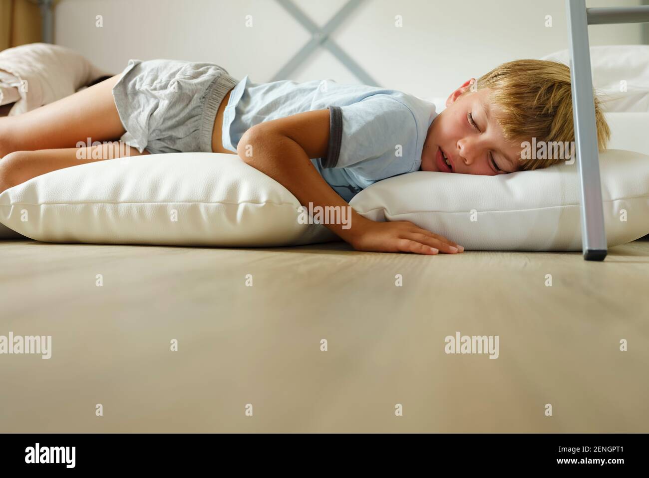 Child in pajamas sleeping in his bed without blankets, illuminated