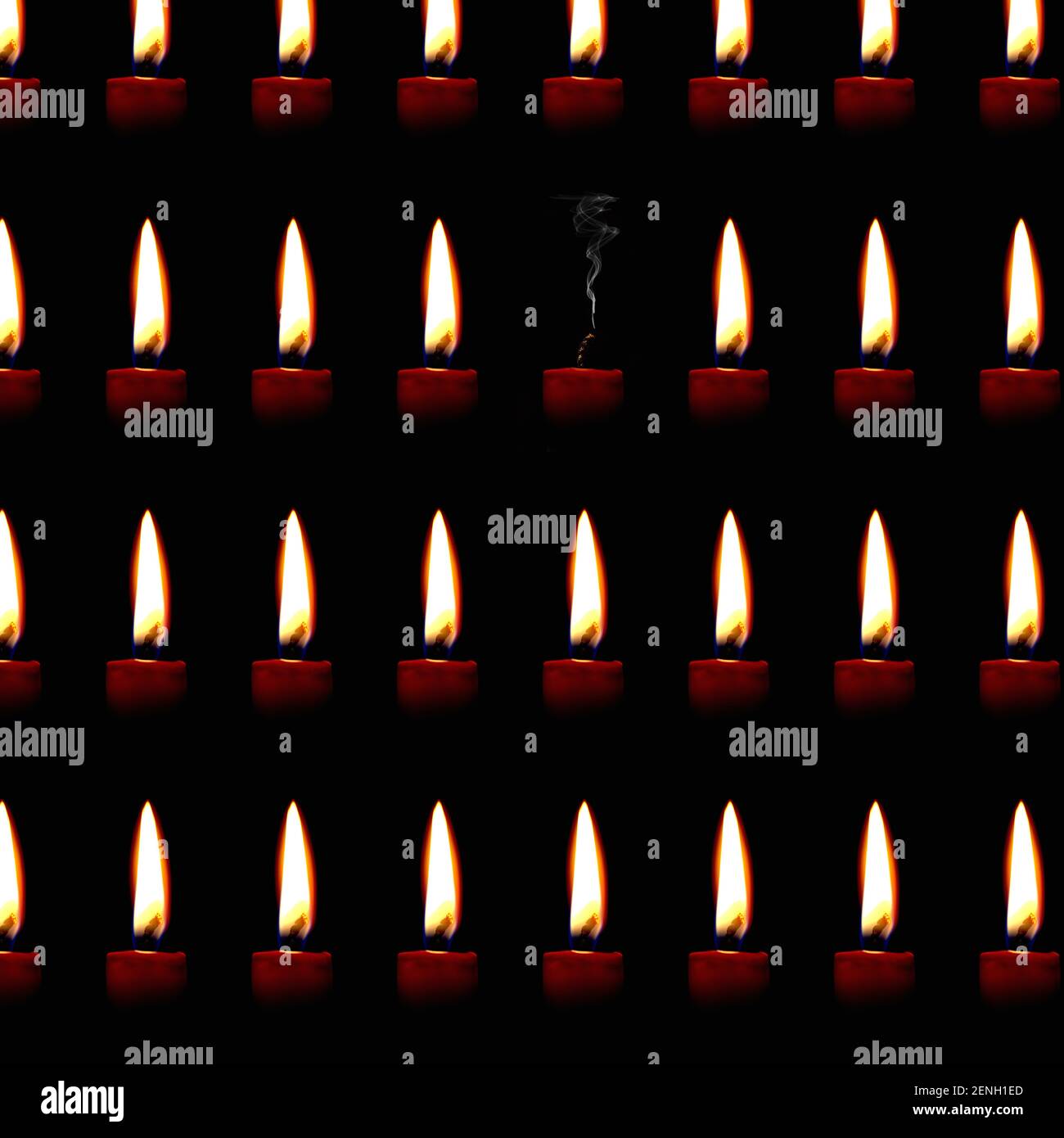Pattern of burning candles with one extinguished candle from which rises a plume of smoke Stock Photo