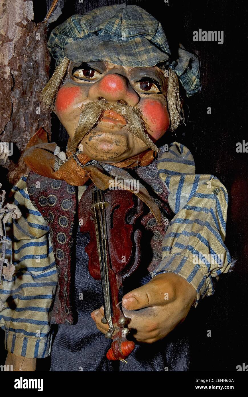 This peasant fiddler with soulful eyes, red cheeks and nose and a drooping walrus moustache wears a stained cloth cap, shirt and waistcoat as he prepares to serenade visitors to one of the traditional mannequin and puppet shops in Prague, capital of the Czech Republic or Czechia.  The male violinist is among many imaginative designs for puppets, marionettes and dolls on offer to visitors that help to maintain vibrant Bohemian folklore and craft traditions stretching back to at least the 1500s. Stock Photo