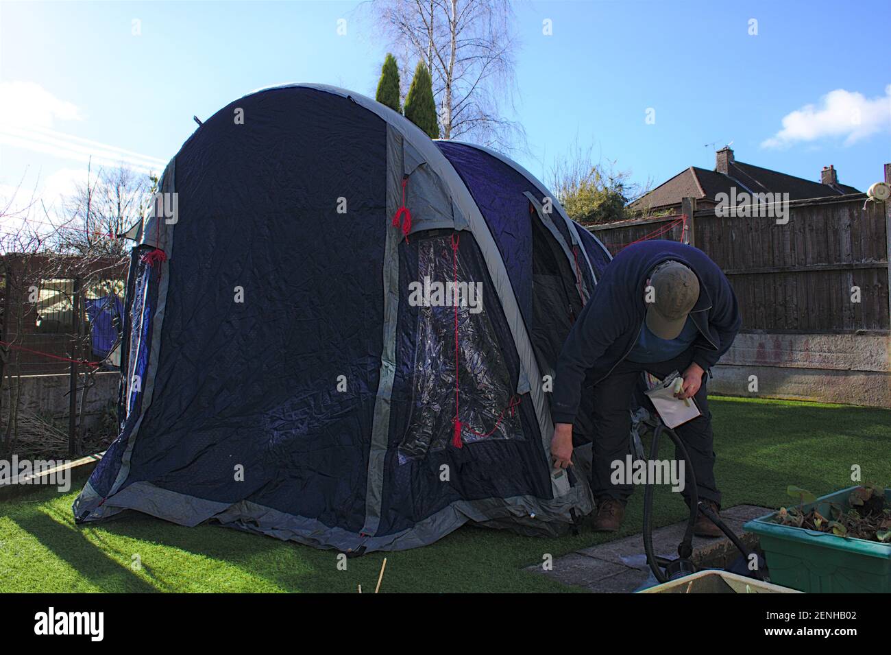 Unidentifiable man inflating a four man ten in a domestic garden, holidaying at home concept Stock Photo