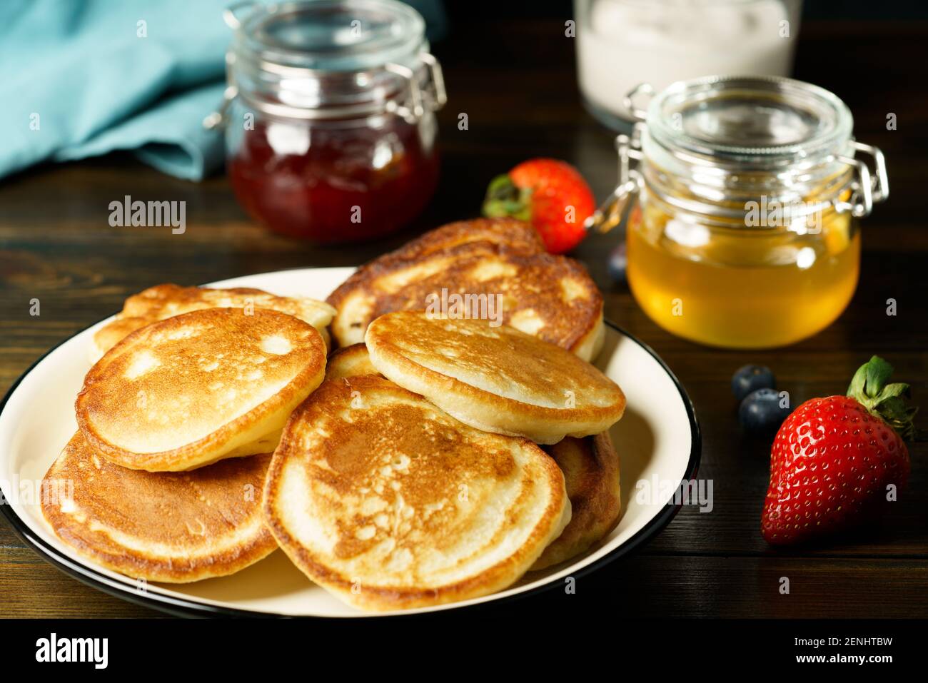 Blini served with strawberry jam, honey, sour cream and fresh berries. Dark wooden table, high resolution Stock Photo