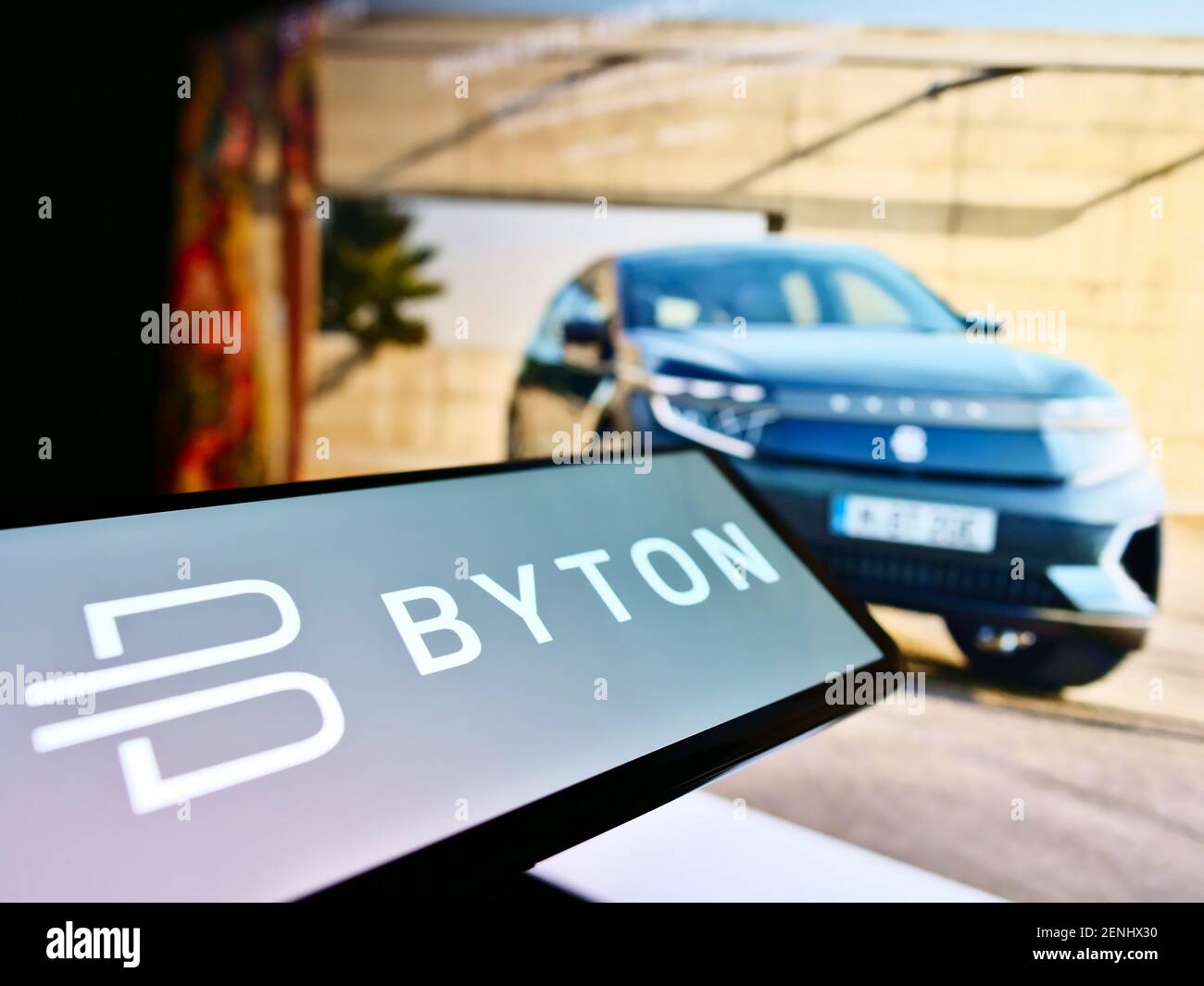 Mobile phone with company logo of Chinese automotive brand Byton (electric vehicle) on screen in front of web page. Focus on center of phone display. Stock Photo