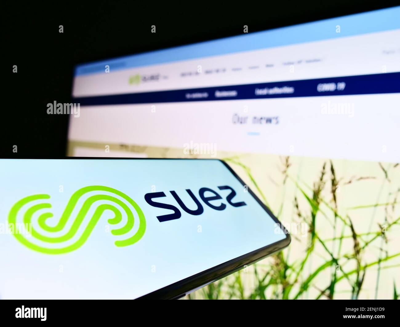 Mobile phone with business logo of French utility company Suez SA on screen in front of web page. Focus on center of cellphone display. Stock Photo