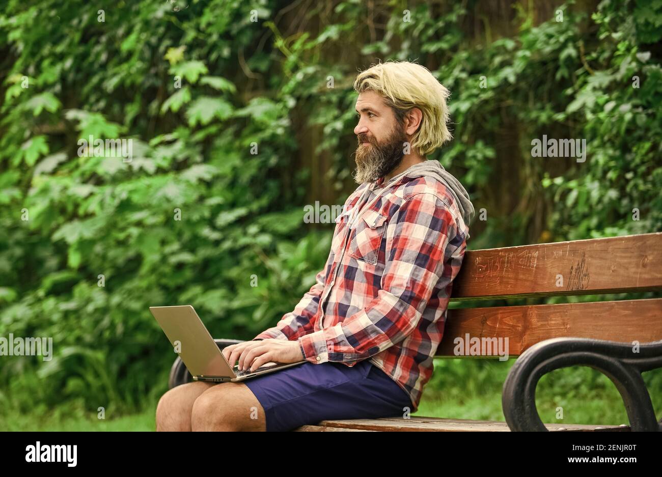 Remote job. Online shopping. Agile business. Bearded guy sit bench park nature background. Work and relax. Working online. Hipster inspired work in park. Fresh air. Mobile internet. Modern laptop. Stock Photo