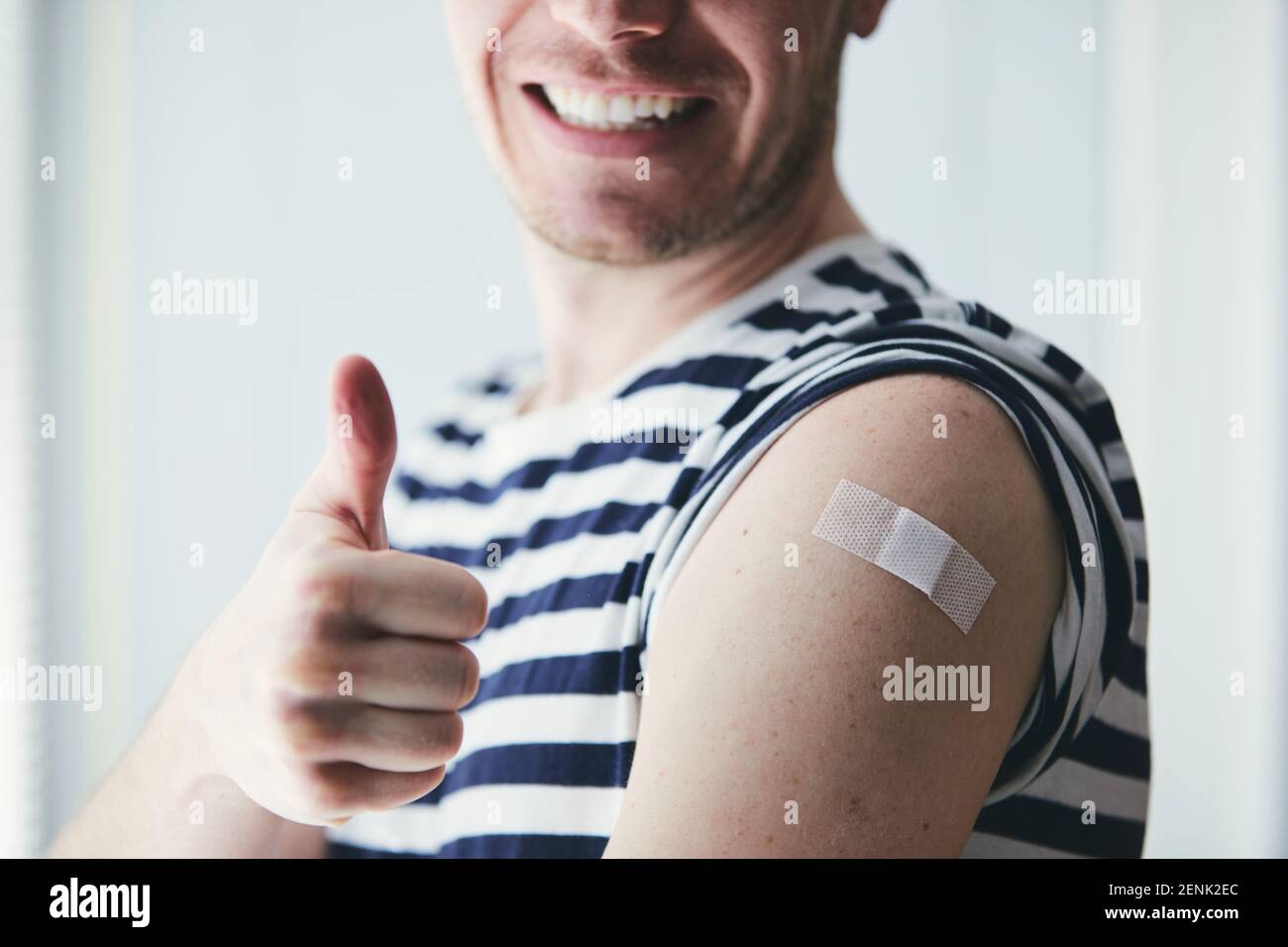 Happy young man showing thumb up and his arm after vaccination. Themes prevention, vaccine and health care during pandemic covid-19. Stock Photo