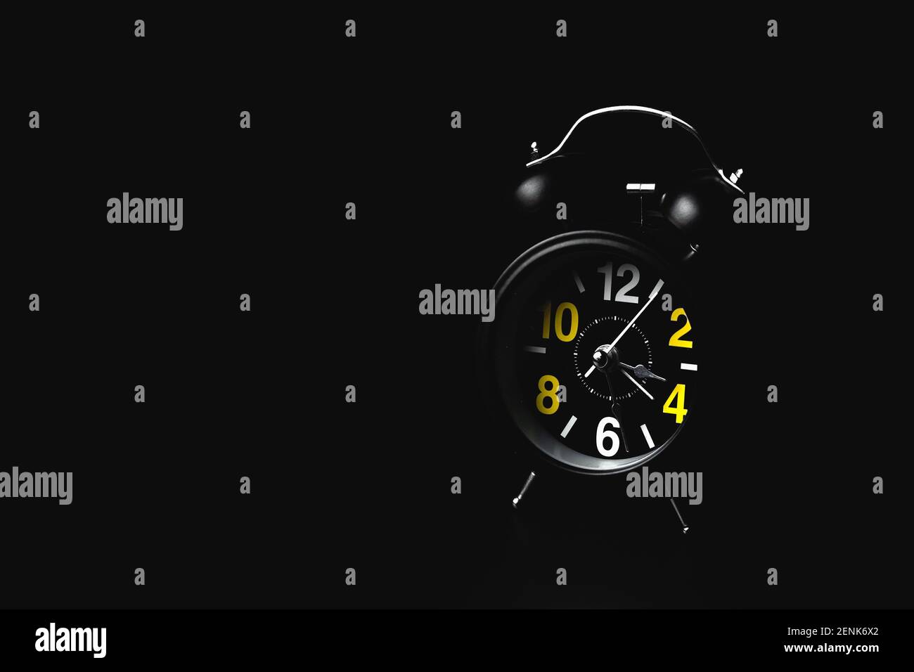 Black round modern alarm clock on black background with copy space. The