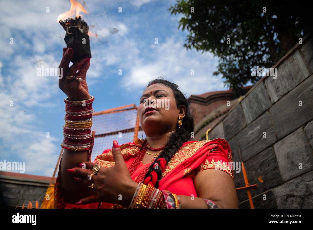 a Nepalese Hindu woman holding a lamp offers prayers at premises of  Pashupatinath Temple during a Teej festival in Kathmandu,Nepal on Monday,2  September 2019. During this festival, Hindu women observe a day-long