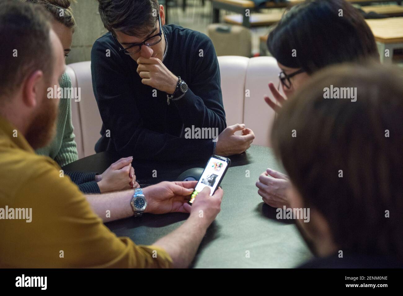 Students sitting together, looking at smart phone Stock Photo