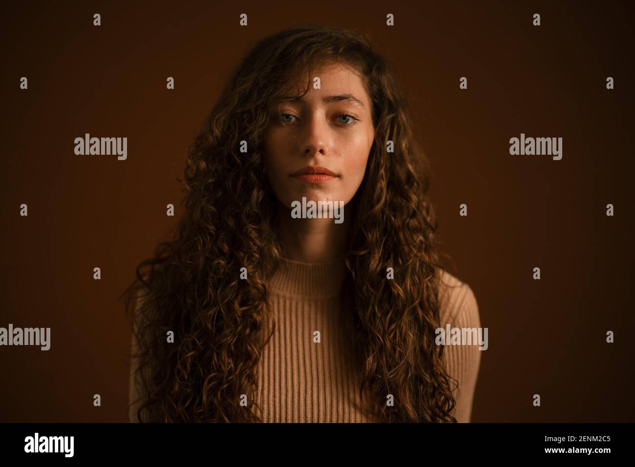 Studio portrait of young woman with long curly Stock Photo - Alamy