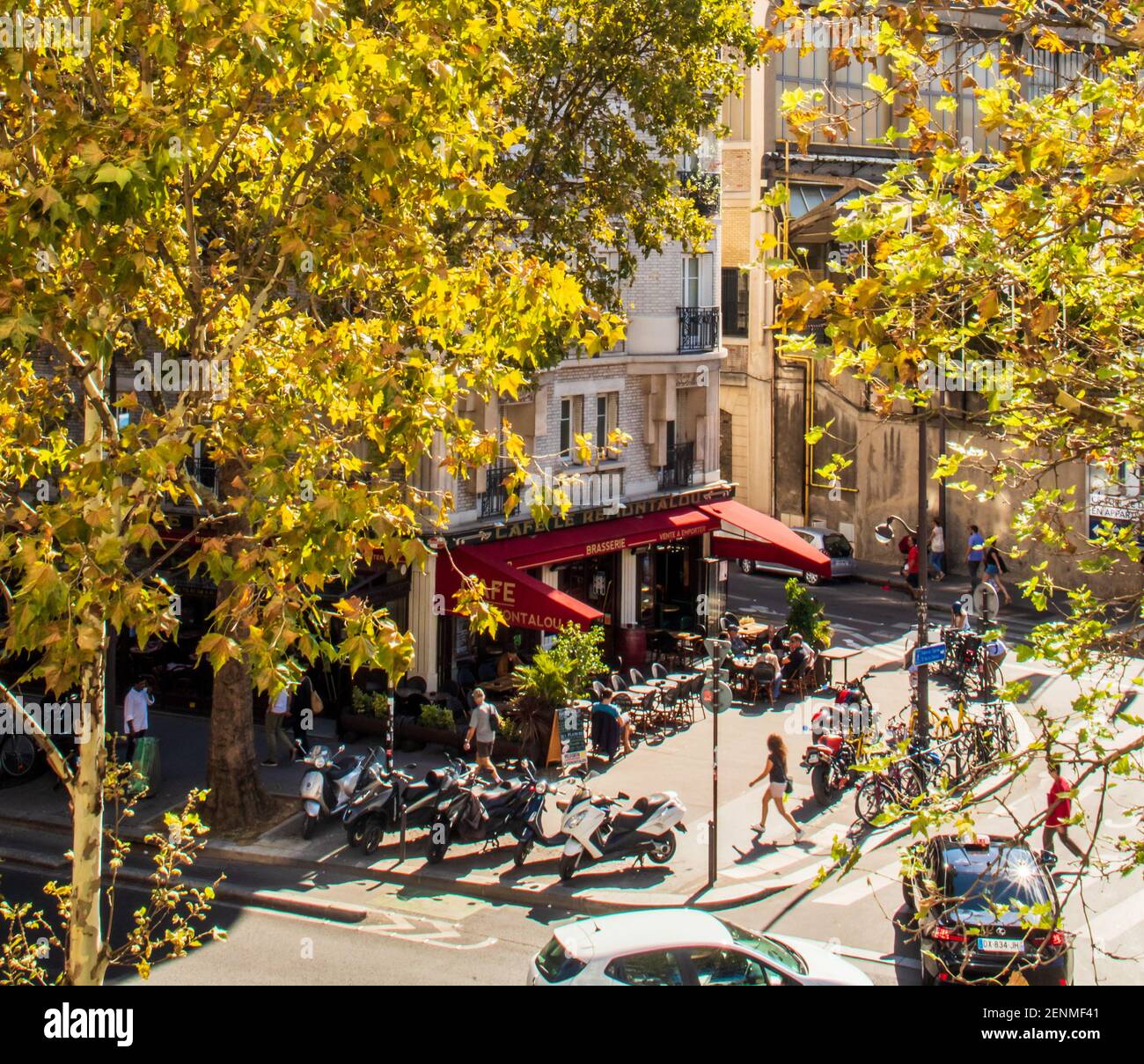 Paris street scene, 12th arrondissement, with fall leaves, people in sidewalk cafe, people walking.  Autumn in Paris, sunny day, bright colors. Stock Photo