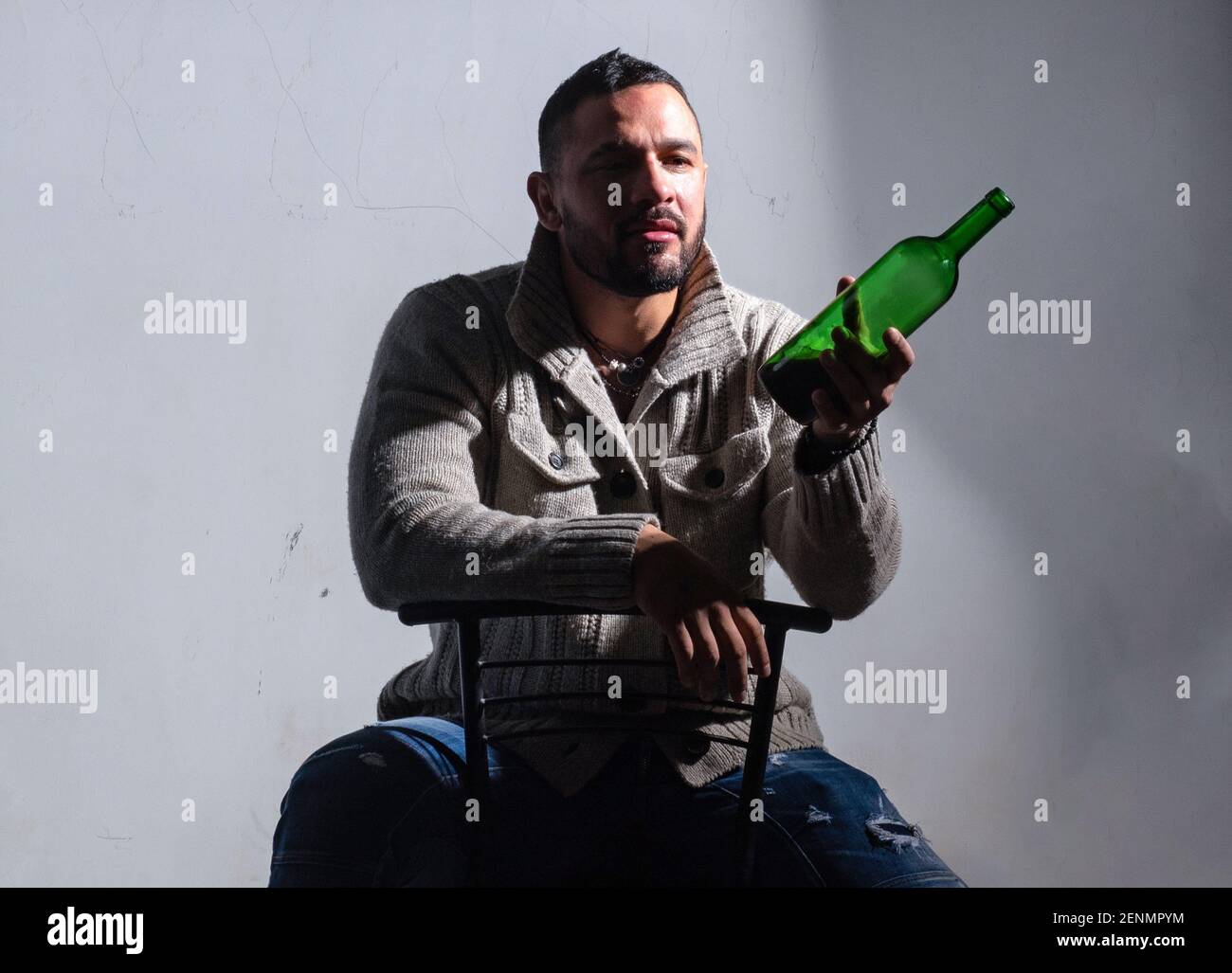 Sad crying drunk man with bottle of alcohol. Hispanic guy feeling