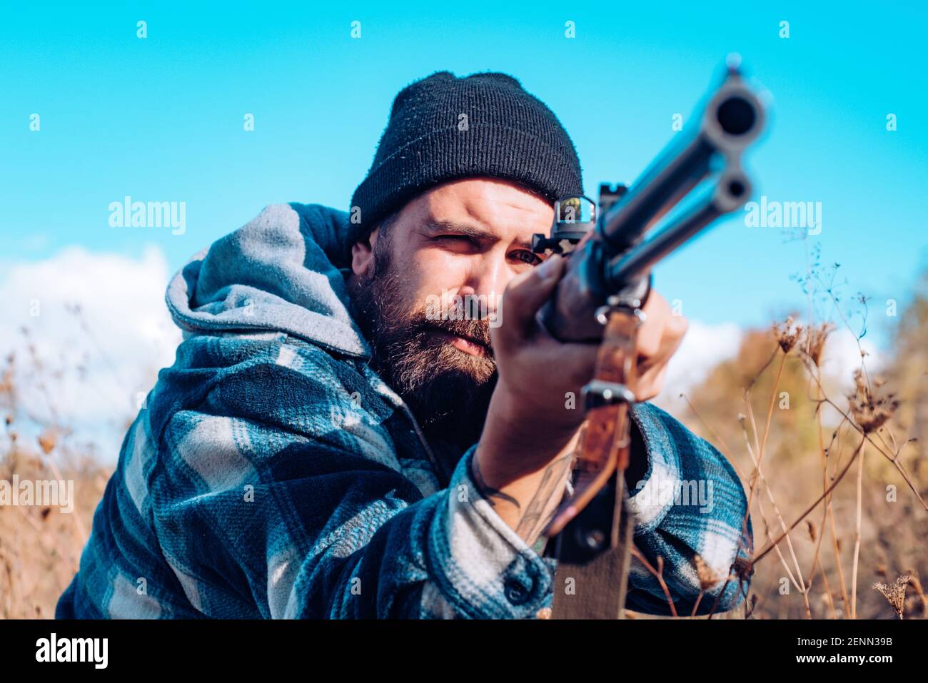 Hunter man hunting in America with shotgun gun on hunt. Aiming rifle in forest. Male with a gun. Stock Photo
