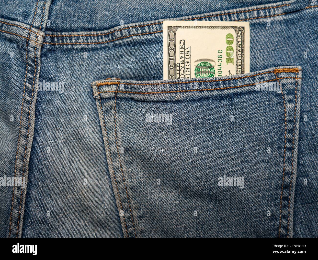a hundred dollar bill sticks out of the back pocket of jeans Stock Photo
