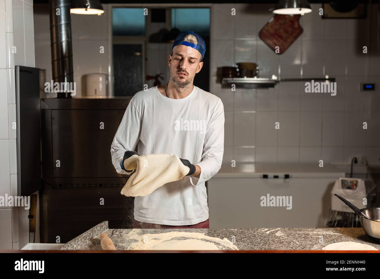 pizza boy kneads pizza dough in a pizzeria restaurant kitchen Stock