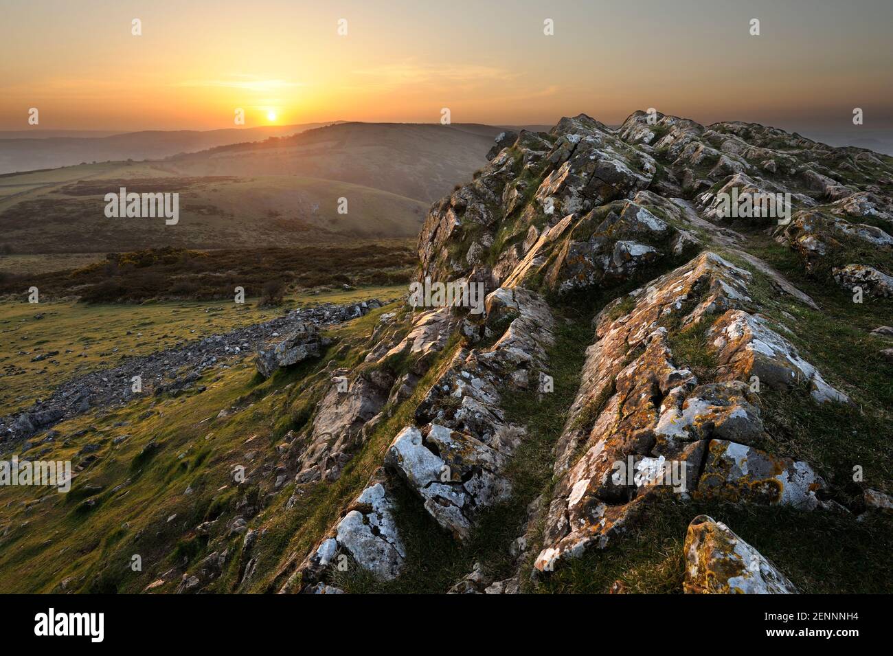 A Spring sunrise seen from the rocky ridge atop Crook Peak on the Mendip Hills in Somerset, UK. Crook Peak, which means 'pointed hilltop', reaches 208 Stock Photo