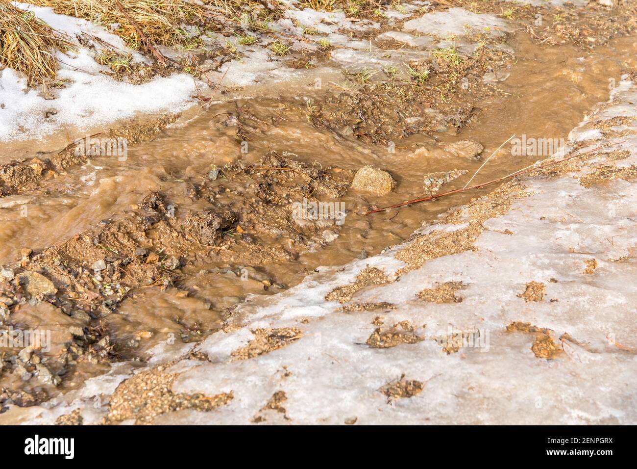 Rural country road covered with melting snow and mud on an early spring day in Czech Republic. Muddy road in the countryside. Melted snow. Stock Photo