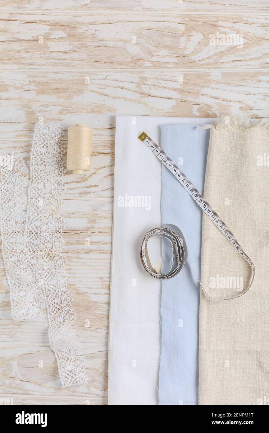 Sewing tools and supplies - fabric and centimeter with thread on wooden table. Stock Photo