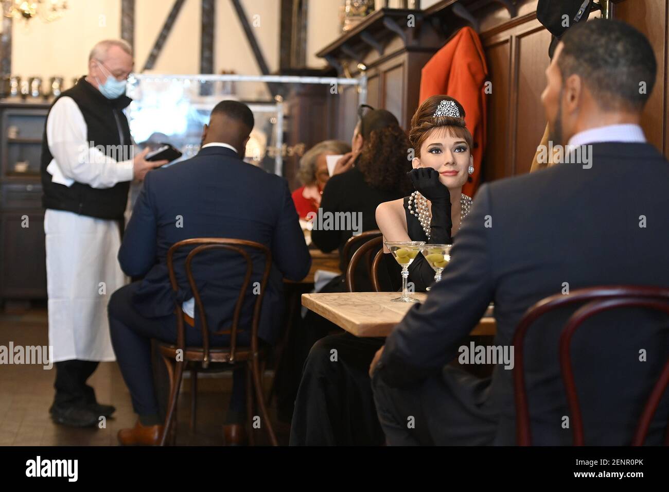 Wax figurines of Audrey Hepburn and Michael Strahan are seated at a