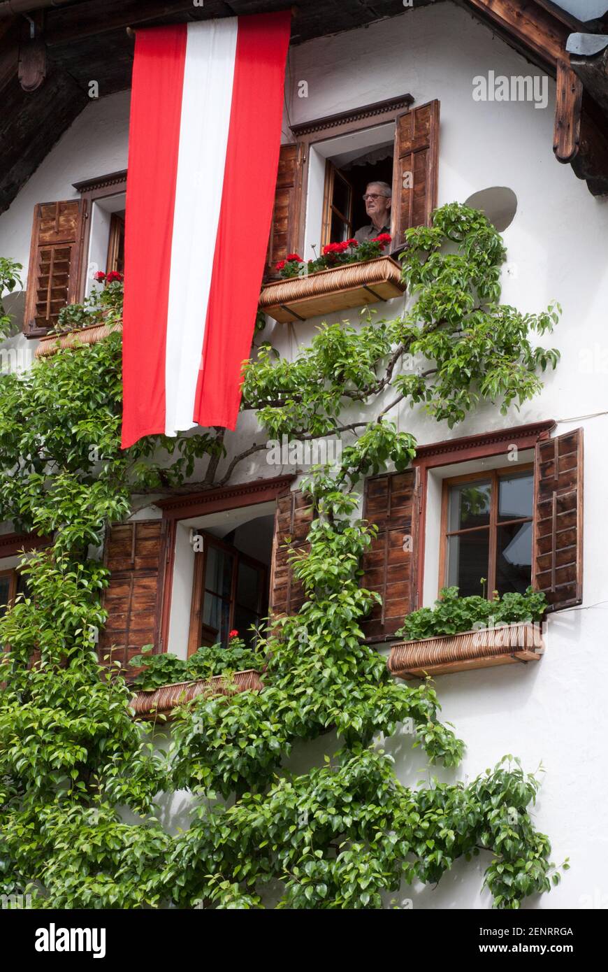 old house on Hallstatt market place with brown shutters, open windows, espalier tree and Austrian flag, Hallstatt, Austria Stock Photo