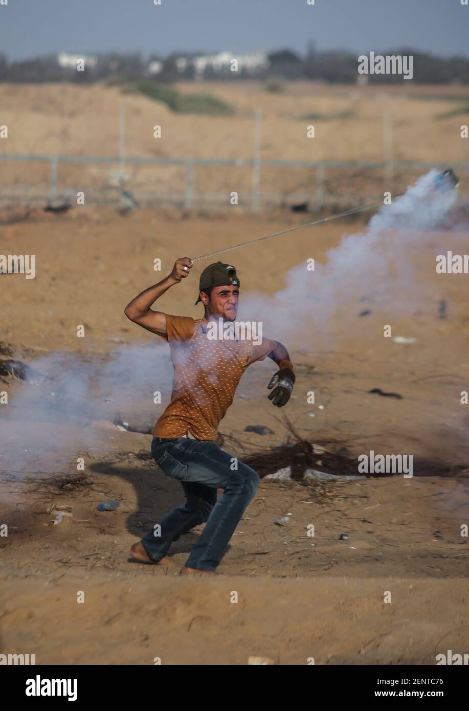 A Palestinian demonstrator uses a slingshot to throw back tear gas
