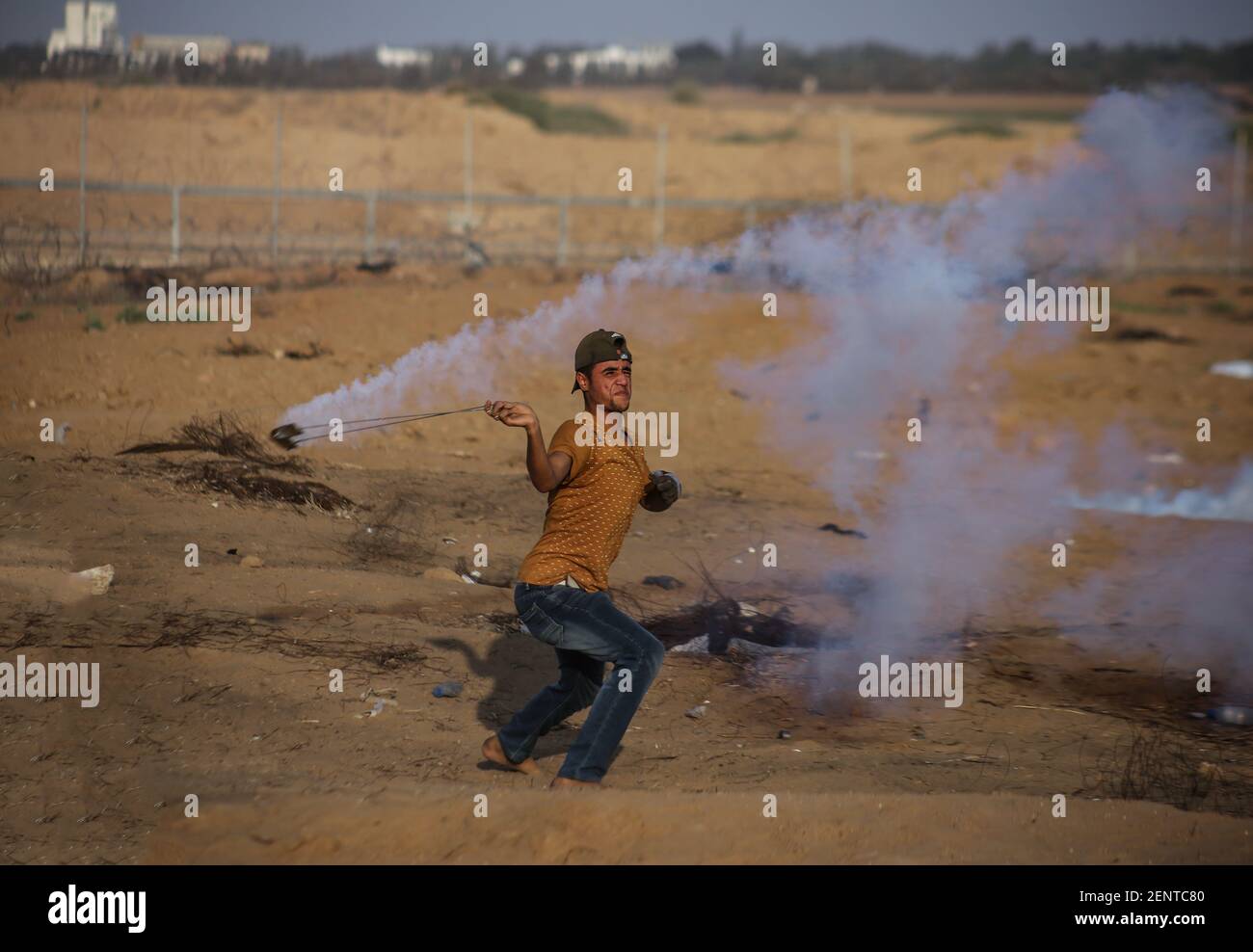 A Palestinian demonstrator uses a slingshot to throw back tear gas