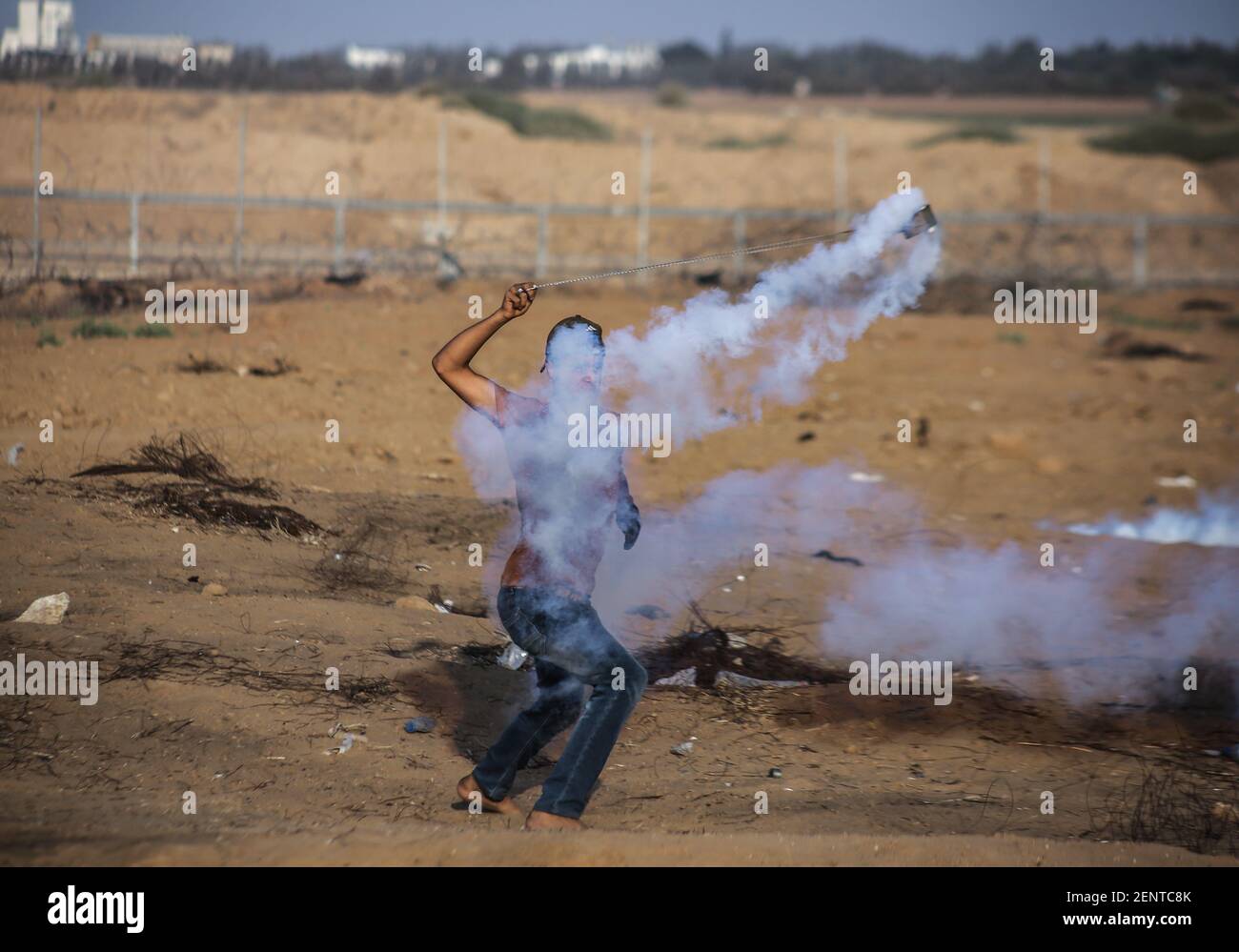 A Palestinian demonstrator uses a slingshot to throw back tear gas