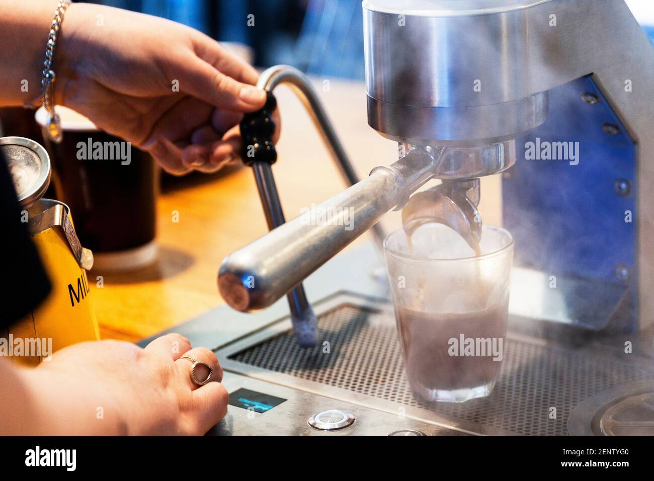 Barista using espresso machine pouring coffee in local cafe Stock Photo