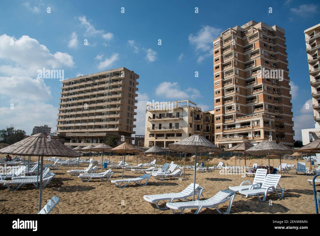 Palm Beach with beach umbrellas and tourists and the abandoned hotels at Varosha ghost town, Famagusta, Northern Cyprus. Stock Photo