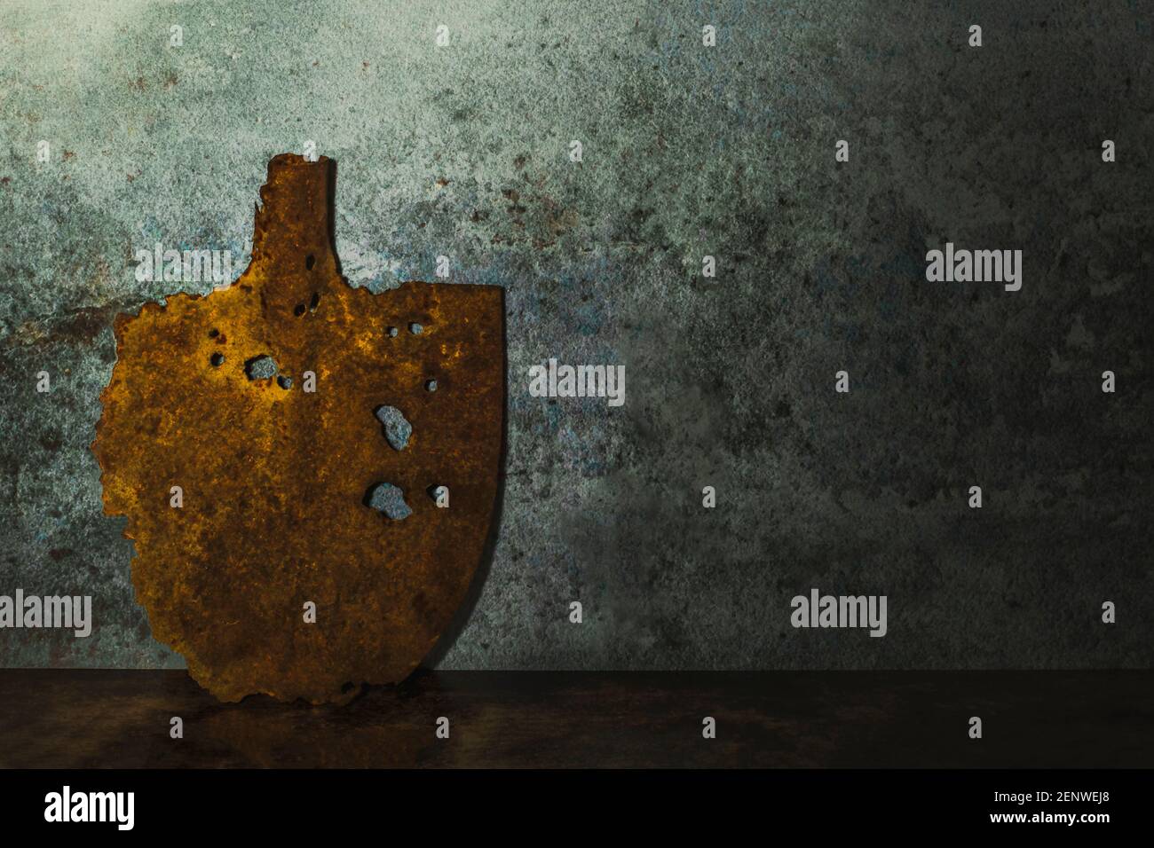 Old vintage, rusty shovel leaning against a grunge wall. Dark gloomy artistic still life photography. Blade antique round digger with empty space. Stock Photo