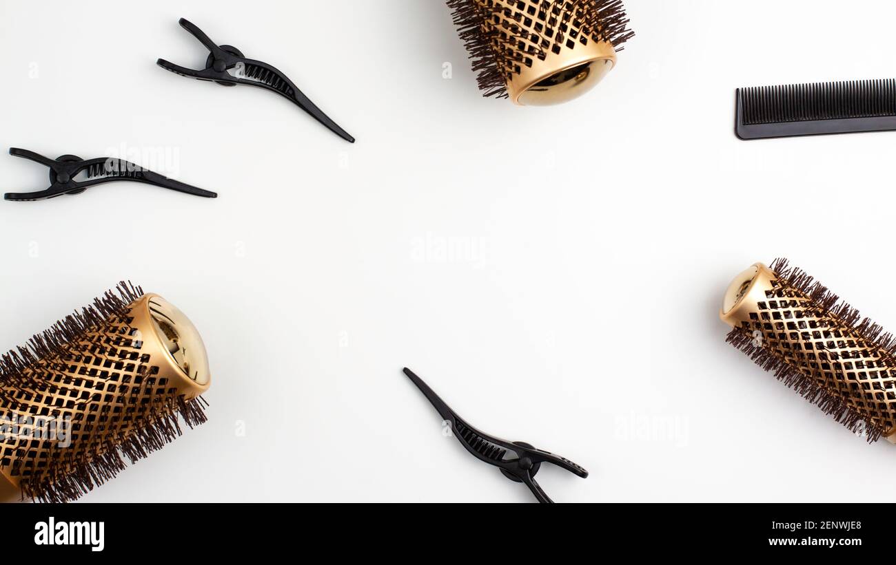 Top view flat lay of tree professional gold round hair brushes for styling,comb for separating hair and section hair clips template with copy space. H Stock Photo
