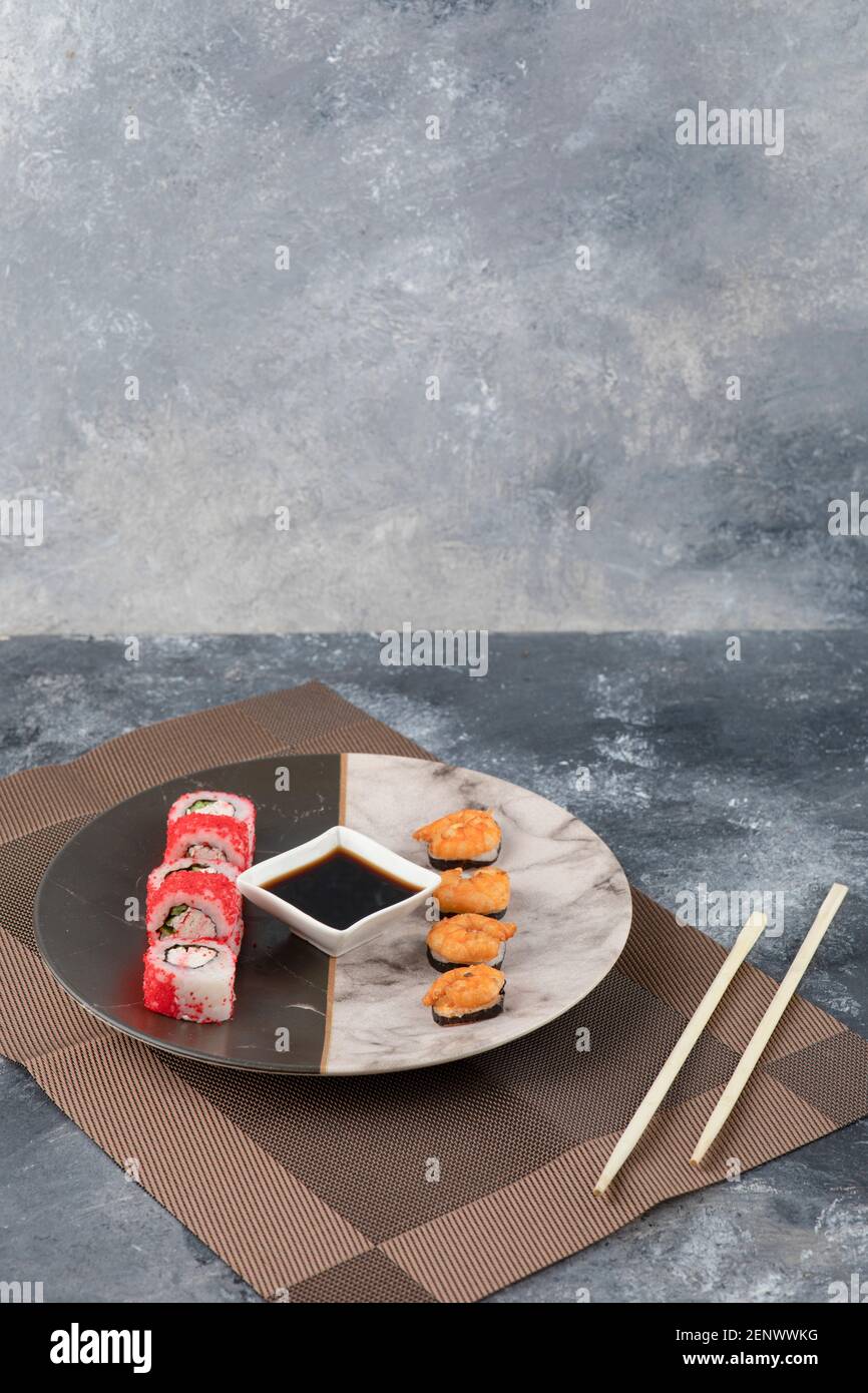 Two kinds of tasty sushi rolls and soy sauce on marble plate Stock Photo