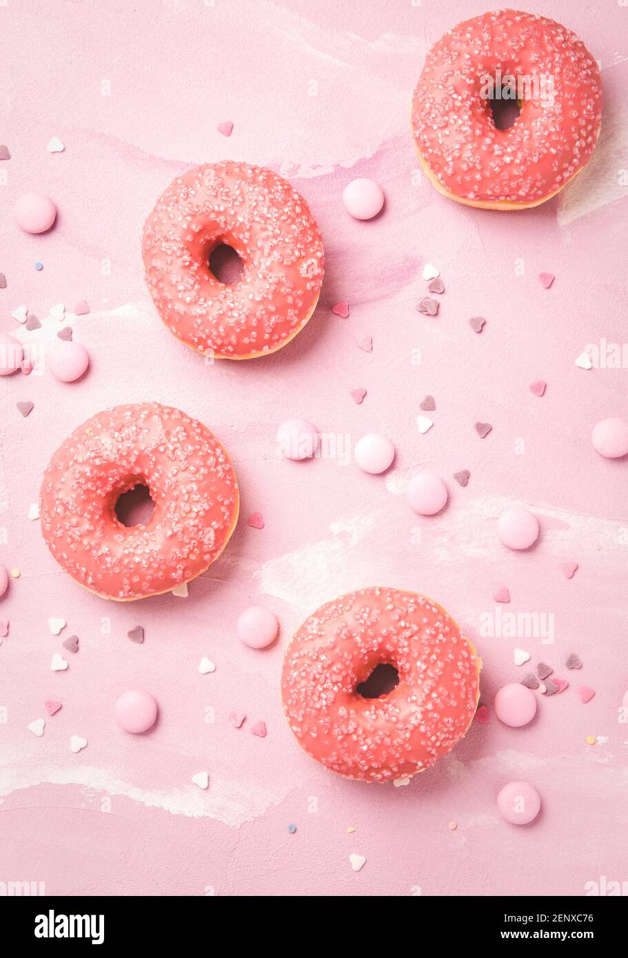 Donuts with pink icing and pink chocolate beans on pink background Stock Photo
