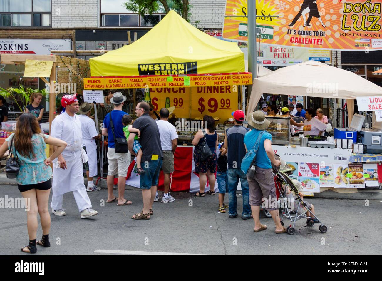 Salsa on St. Saint Clair Festival Scenes: Customers line up at outdoor food stand selling Mexican food. Some of the people are taking time to read the Stock Photo