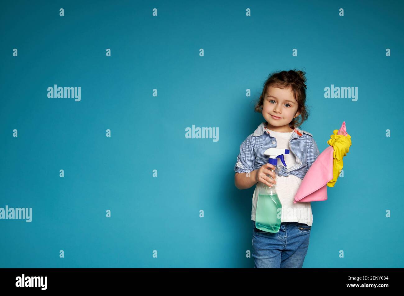 A cute little girl holds a rag to wipe the dust and spray with