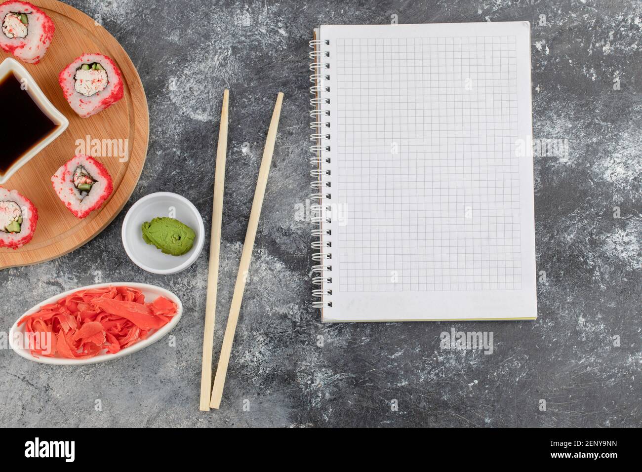 Tasty sushi rolls with red caviar on wooden board with notebook Stock Photo
