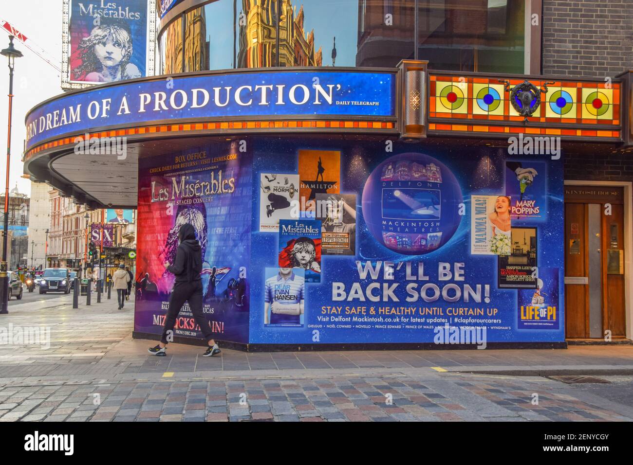 A woman walks past a 'We'll Be Back Soon' sign at Sondheim Theatre on Shaftesbury Avenue, which has been closed for much of the time since the coronavirus pandemic begun. London, United Kingdom February 2021. Stock Photo