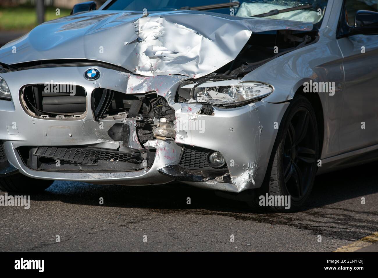 Red paint can be seen on the hood of this Beamer after it smashed into the back of a double-decker bus on a busy city road. Stock Photo