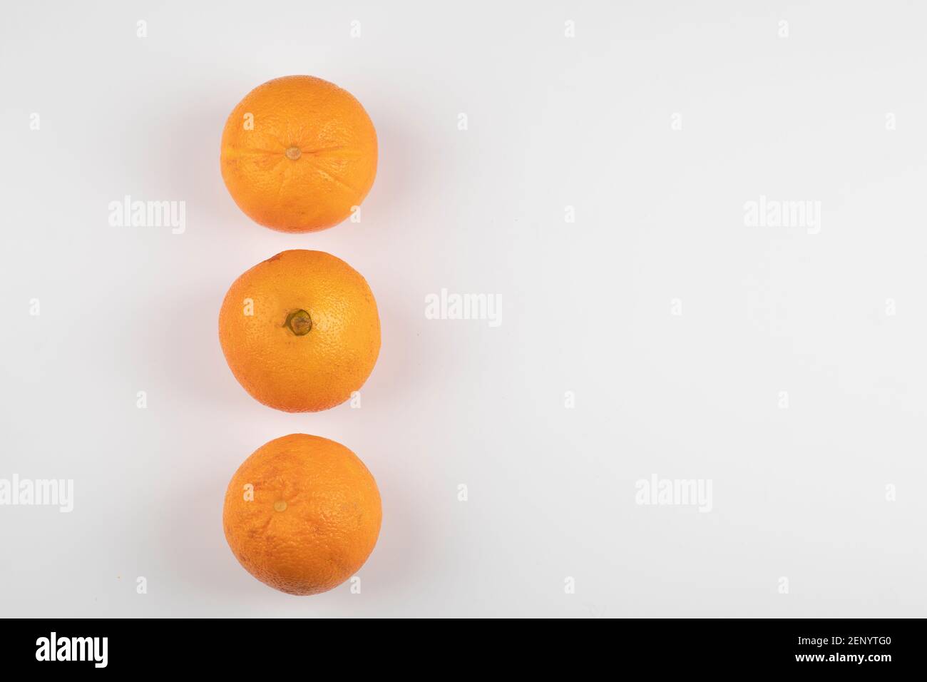 Three whole fresh oranges placed on white table Stock Photo