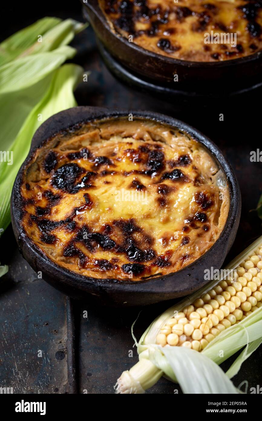 Chilean food. Traditional Pastel de Choclo corn pie. Beef meat with onion, chicken and egg covered with ground corn in clay bowl, top view Stock Photo