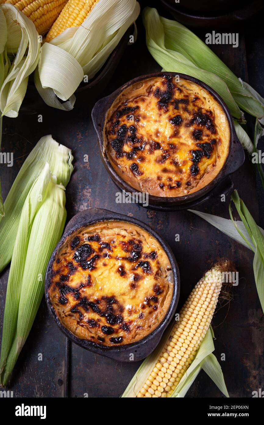 Chilean food. Traditional Pastel de Choclo corn pie. Beef meat with onion, chicken and egg covered with ground corn in clay bowl, top view Stock Photo