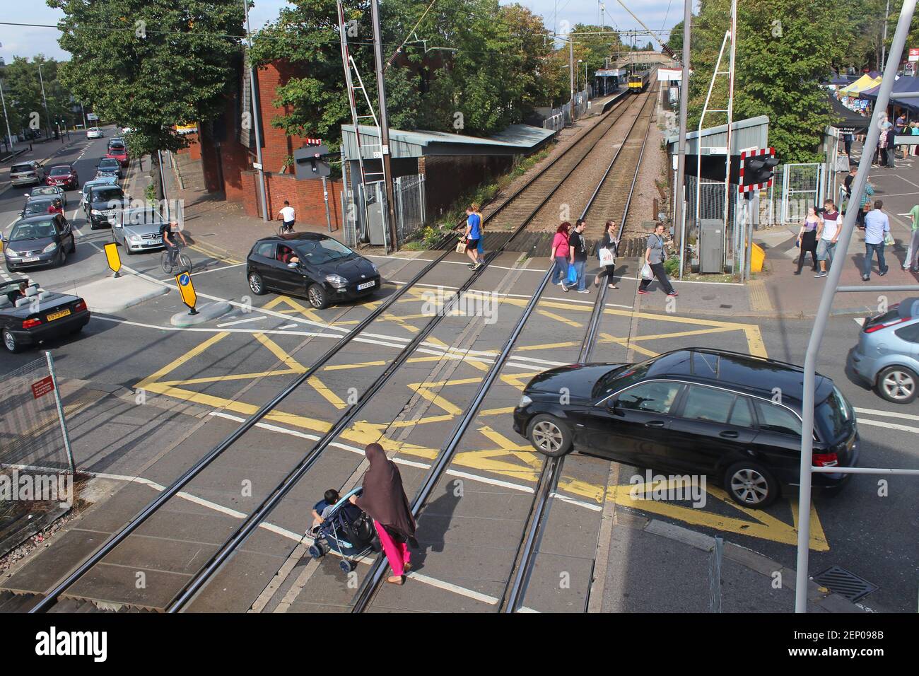 A railway level crossing with cars and pedestrians crossing the track