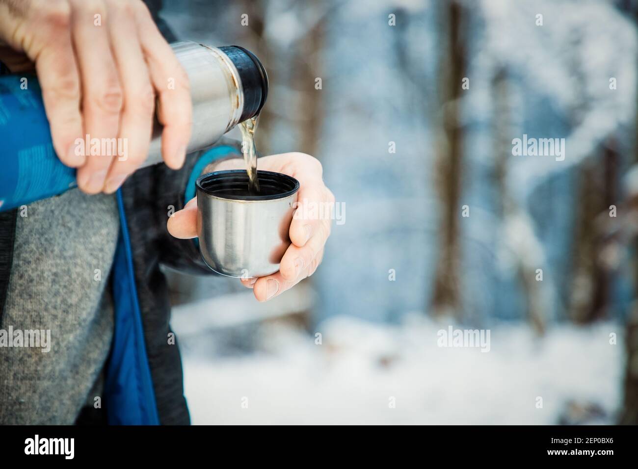 man pouring hot tea in winter forest Stock Photo