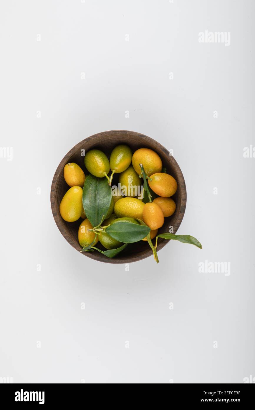 Wooden bowl of yellow kumquats with leaves on white background Stock Photo Alamy