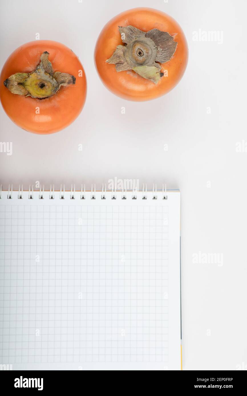 Two persimmon kaki fruits and paper on white background Stock Photo